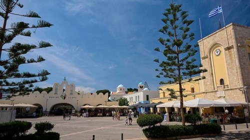 Public square with cafés and striking architectural elements under a blue sky, Eleftherias Square,