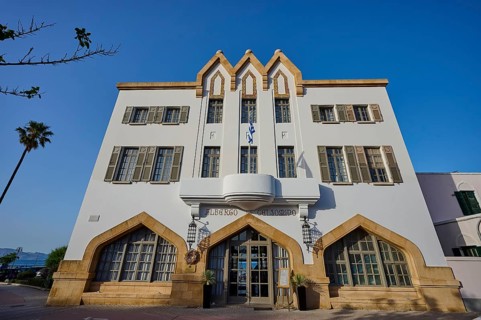 Historic building with striking architecture and symmetrical windows against a blue sky, boutique