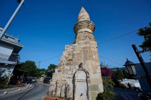 Stone tower and fountain on a street under a blue sky, historical flair, Eski Cami, Minaret, Kos
