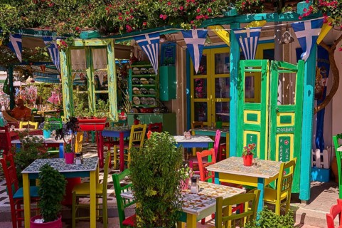 Colourfully decorated taverna with open doors and plants, summery and friendly atmosphere, Platia