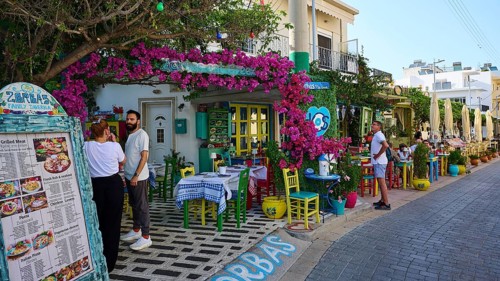 Guests sitting outside in front of a tavern decorated with flowers in kos, friendly atmosphere,