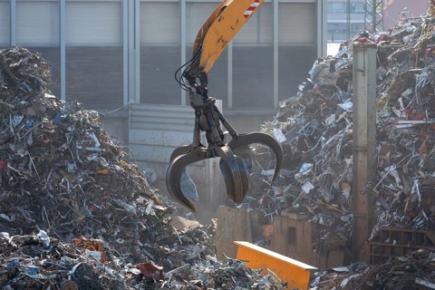 Hydraulic crane lifts scrap metal at the scrap yard