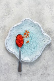 A spoon with orange flying fish caviar, Tobiko, on a light blue plate, caviar for rolls and sushi,
