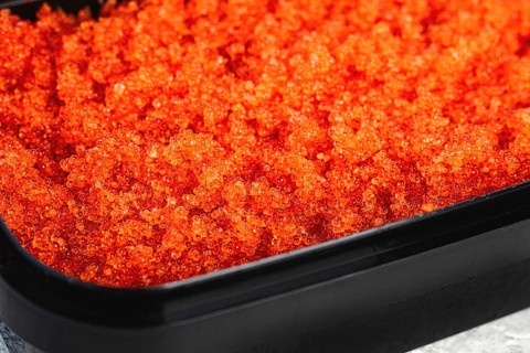 Container with orange caviar, flying fish, Tobiko, on the table, caviar for rolls and sushi,