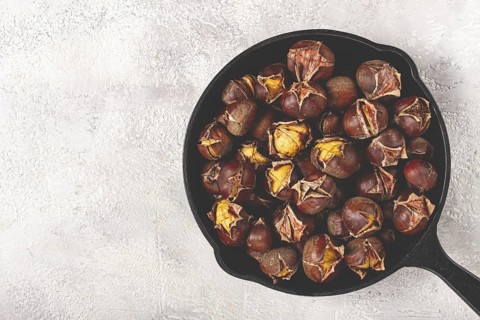 Roasted chestnuts, in an iron pan, wooden table, top view, no people, rustic style