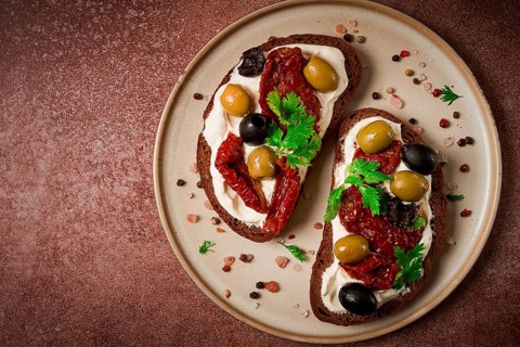 Sandwich with cream cheese, dried tomatoes, olives, breakfast, top view