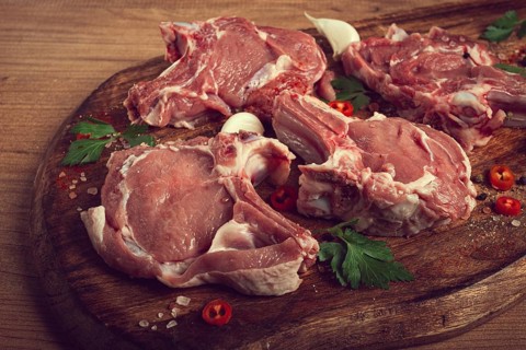 Raw calf meat, meat on the bone, meat for barbecue, cutting board, with spices and herbs, top view