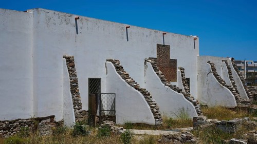 ©Udo Rein, White antique building with exposed stone walls under a blue sky, exterior view, Casa
