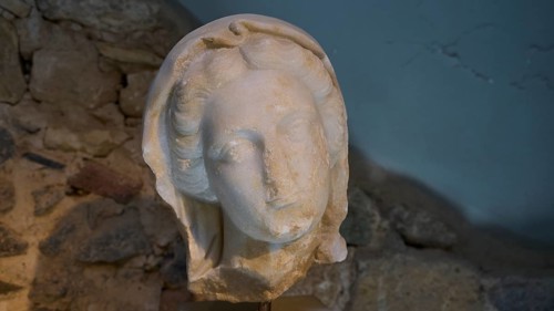 ©Udo Rein, Ancient stone sculpture of a head in front of a rock face, Faustina, Casa Romana, Kos