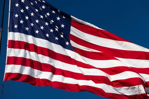 American flag waving in the wind against deep blue sky
