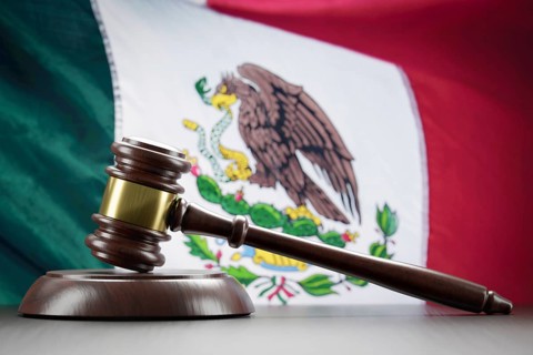 Wooden gavel resting on table in front of mexican flag