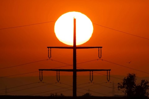 The sun rises behind an electricity pylon near Frankfurt am Main, Frankfurt am Main, Hesse, Germany