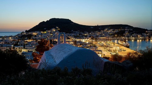 Chapel Agia Paraskevi, town with harbour at dusk, illuminated, hill in the background, Skala,