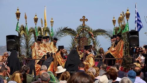 A procession of priests in golden robes, surrounded by palms and religious symbols, holds an