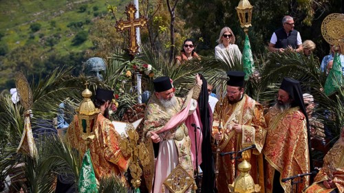 Priests in elaborate robes and incense burners stand in the light of numerous candles during a