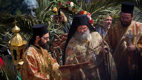 Priests in magnificent robes celebrate a religious ritual surrounded by palm trees and a festive