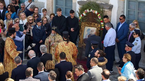 Priests and people gather in a ceremony around an icon, some wearing traditional vestments, others