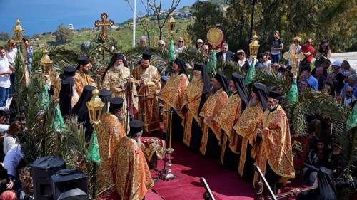 Solemn outdoor religious ceremony with Orthodox priests in gold-decorated robes, surrounded by