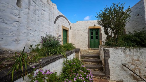 Inner courtyard with whitewashed walls, green doors and flowering plants, Monastery of the