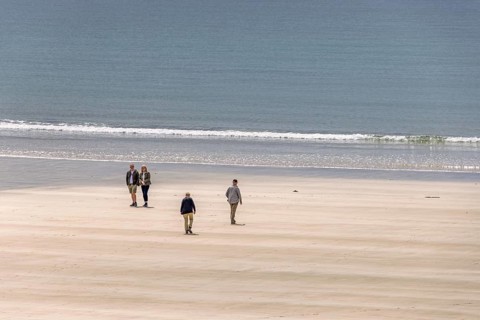 People walking on a sand beach by the sea a sunny summer day, Crozon peninsula, Bretagne, France