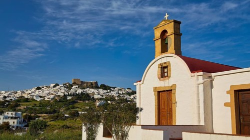White chapel with cross and wooden door, village in the distance, chapel south of the Chora, World