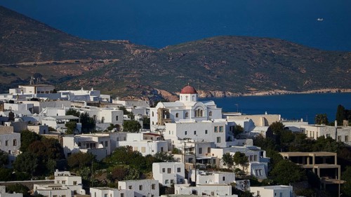 Whitewashed church with red roof in front of a coastal landscape and blue sea, World Heritage Site