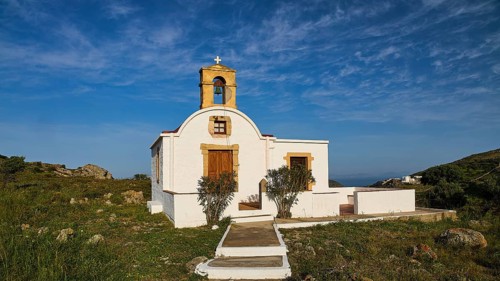 White chapel with bell tower in a rural, Mediterranean setting under a blue sky, chapel south of