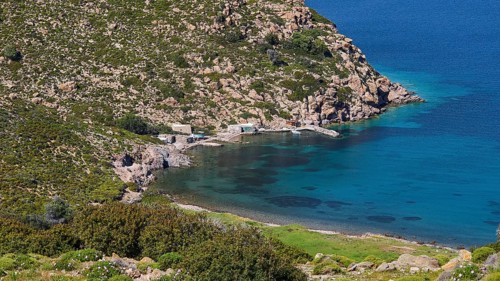 Small harbour bay with crystal clear water surrounded by rocky landscape and lots of greenery,