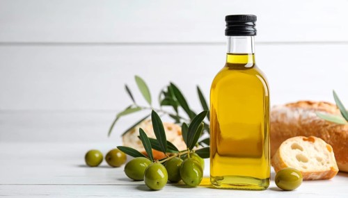 Bottle of fresh olive oil with branch with green olives and ciabatta, closeup, white wooden table,