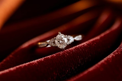 Close-up of diamond ring on red velvet with soft warm lighting and luxurious texture. Generative
