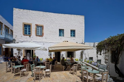 People sitting at tables under parasols on a sunny café terrace, Platia Lesvias, Chora, UNESCO