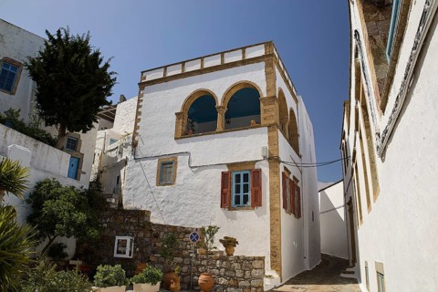 White house with striking balcony and brick details under a clear blue sky, Lion's Alley, Captain's