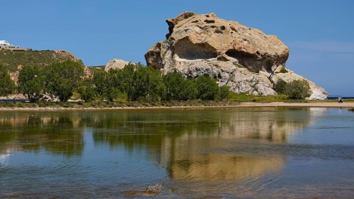 Elevated rock with its reflection in the calm lake on a sunny day, Seasonal salt lake, Rock of