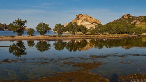 Rocks and trees reflected in a calm lake under a clear sky, Rocks of Kalikatsou, Seasonal Salt