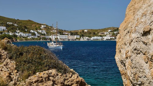 Sailing boat in a bay, surrounded by rocks and white buildings on the shore, Grikos, Rock of