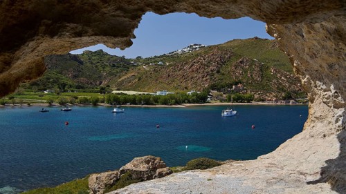 View from a cliff to the calm sea with boats and a green hilly coastal scene, cave, Chora, Grikos,