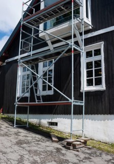 A building with white, carved mullioned windows, windows, and a black wooden facade over a white
