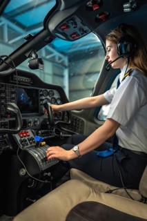 Confident female pilot skillfully operating controls of a modern aircraft within the cockpit,