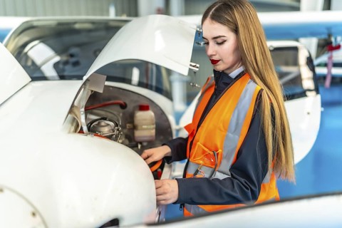 Aircraft maintenance engineer performing a pre flight inspection on a light aircraft engine in a