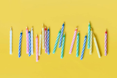 Colorful birthday candles in a row on yellow background