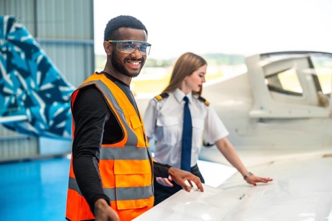 Smiling aircraft maintenance engineer and pilot inspecting airplane wing, ensuring safety and