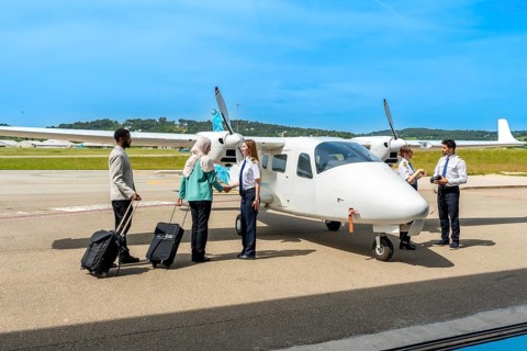 Passengers with luggage shaking hands with female pilot before boarding small private airplane on