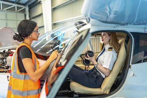 Aircraft maintenance supervisor taking notes while talking to female pilot preparing for flight,