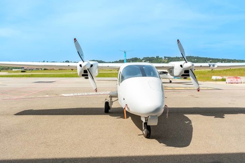 White twin engine turboprop airplane is parked on the tarmac of a small airport on a sunny day,