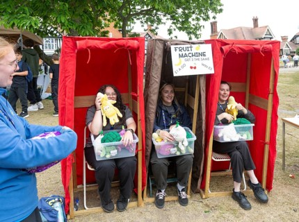 Three women forming human fruit machine game at village summer fete, Bawdsey, Suffolk, England, UK