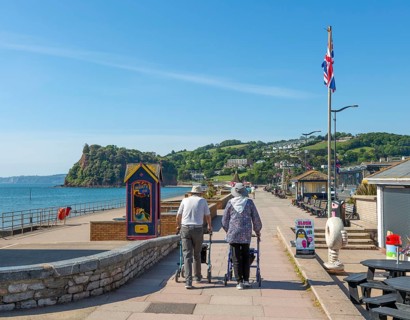 Two elderly people walking with rollators, Seafront promenade view west towards Teignmouth, south