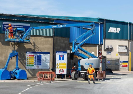 Man on cherry picker machinery cleaning sign, Port of Teignmouth, Teignmouth, south Devon, England,
