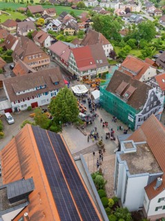 Aerial view of a village square with people and traditional buildings with tiled roofs, family