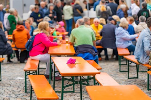 Outdoor event with beer tables and guests, one table is decorated with a pink flower, family party