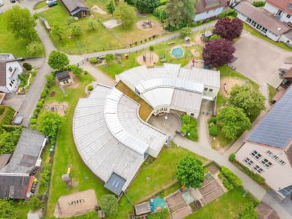 Bird's eye view of modern-style building complex with surrounding green and play areas, family